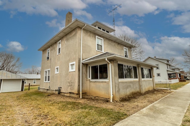 view of side of home featuring a garage, an outbuilding, and a lawn