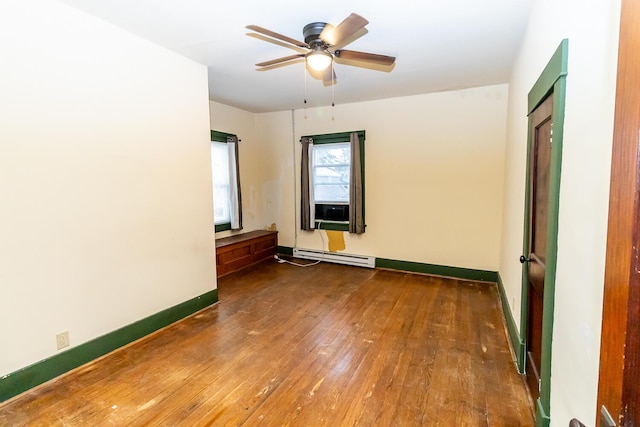 empty room featuring dark hardwood / wood-style flooring, a baseboard radiator, and ceiling fan