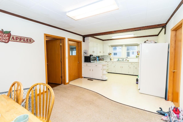 kitchen with white cabinetry, sink, white refrigerator, ornamental molding, and light carpet