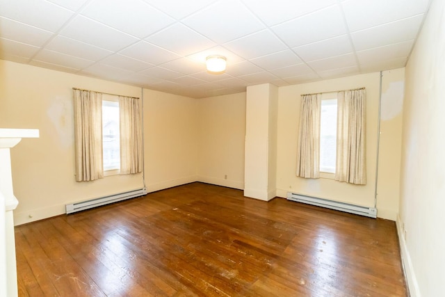 spare room featuring dark hardwood / wood-style flooring, a baseboard heating unit, and a paneled ceiling