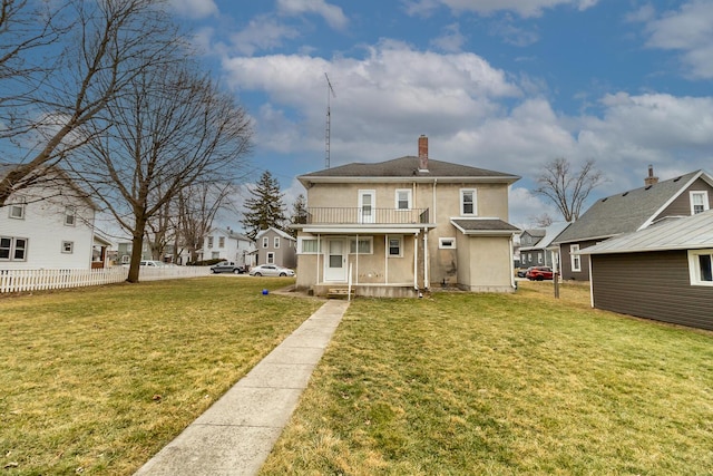 rear view of property featuring a balcony and a lawn