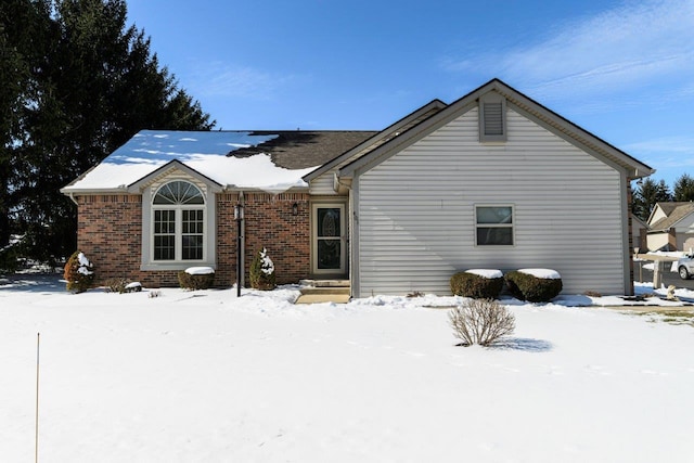 snow covered property featuring brick siding