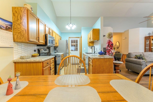 kitchen with stainless steel appliances, light countertops, backsplash, open floor plan, and a sink