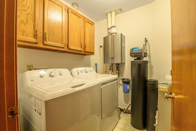 washroom with tankless water heater, cabinet space, washer and clothes dryer, and light floors