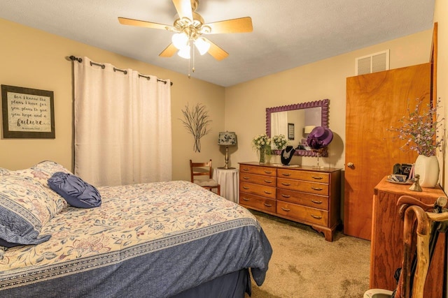 carpeted bedroom with ceiling fan, visible vents, and a textured ceiling