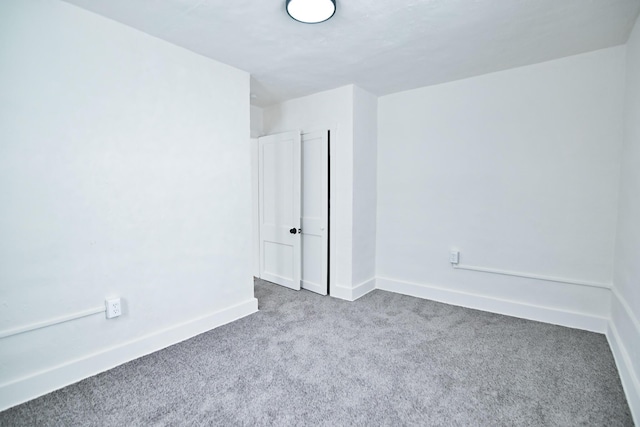 carpeted empty room featuring baseboards