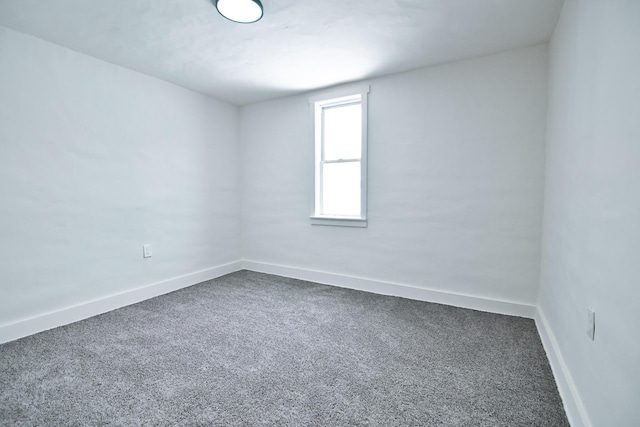 empty room with baseboards and dark colored carpet