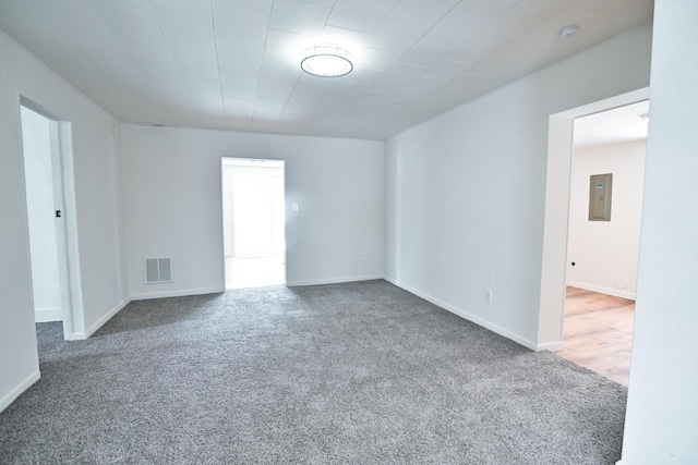 spare room with electric panel, visible vents, baseboards, and carpet