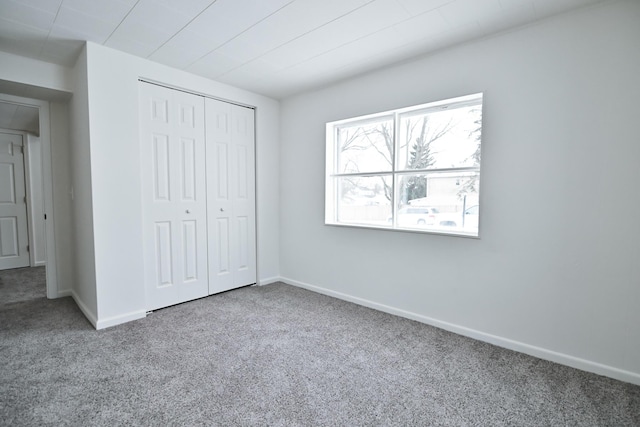 unfurnished bedroom with carpet, a closet, and baseboards