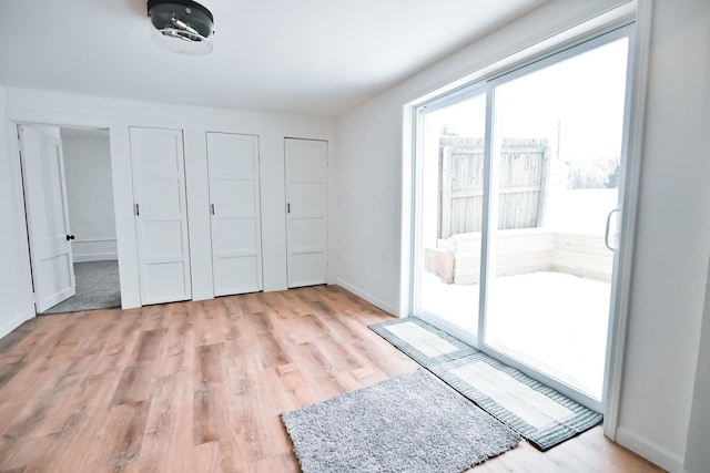 unfurnished bedroom with access to exterior, baseboards, and light wood-type flooring