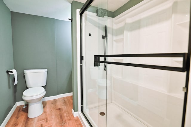 full bathroom with toilet, wood finished floors, a stall shower, and baseboards