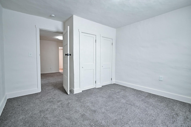 unfurnished bedroom featuring baseboards, carpet floors, and a closet