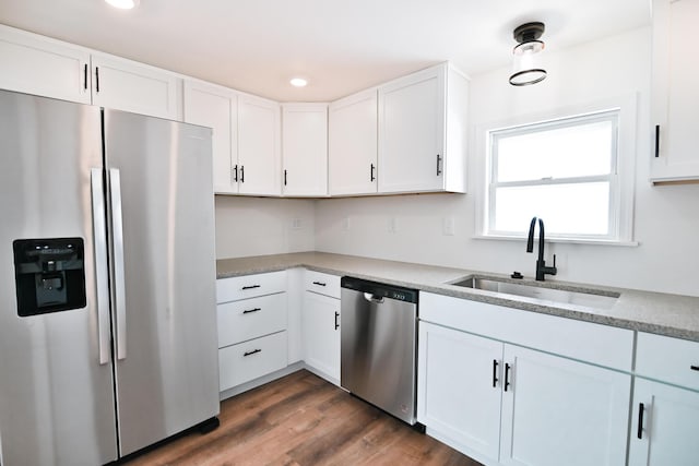 kitchen featuring wood finished floors, recessed lighting, a sink, stainless steel appliances, and white cabinetry