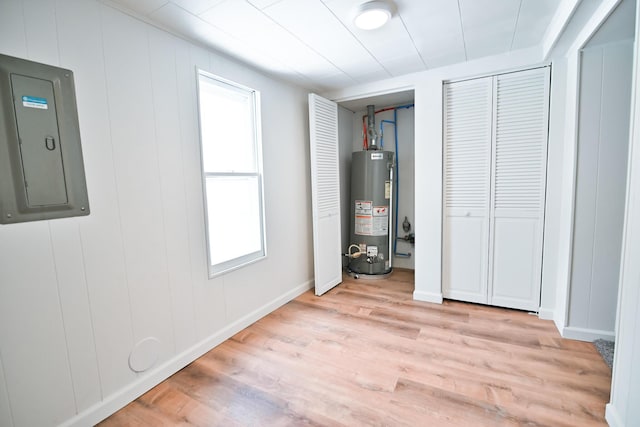 unfurnished bedroom with electric panel, gas water heater, two closets, and light wood-type flooring