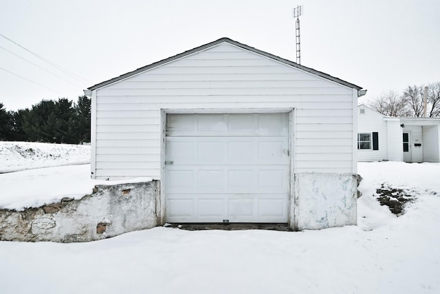 snow covered garage featuring a detached garage