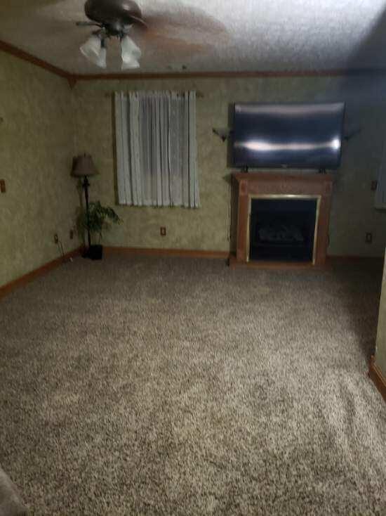 1607 Nagel St, Saint Marys, OH 45885 - unfurnished living room featuring carpet, baseboards, a fireplace, ornamental molding, and a ceiling fan