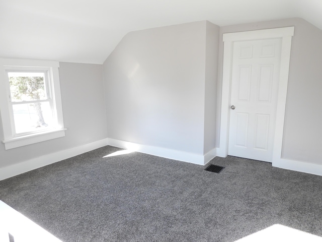 additional living space with vaulted ceiling, carpet, visible vents, and baseboards