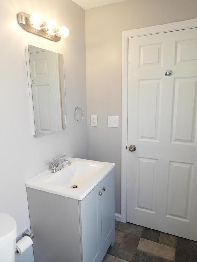 bathroom featuring vanity, stone finish floor, and toilet