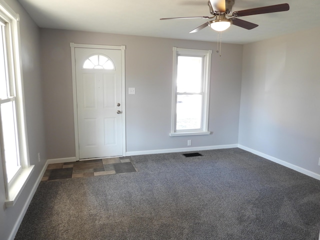 carpeted foyer entrance featuring visible vents, baseboards, and a ceiling fan