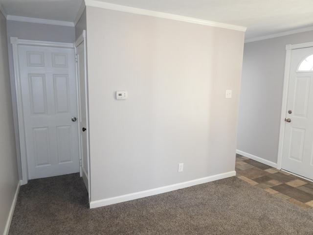 foyer featuring dark carpet, baseboards, and ornamental molding