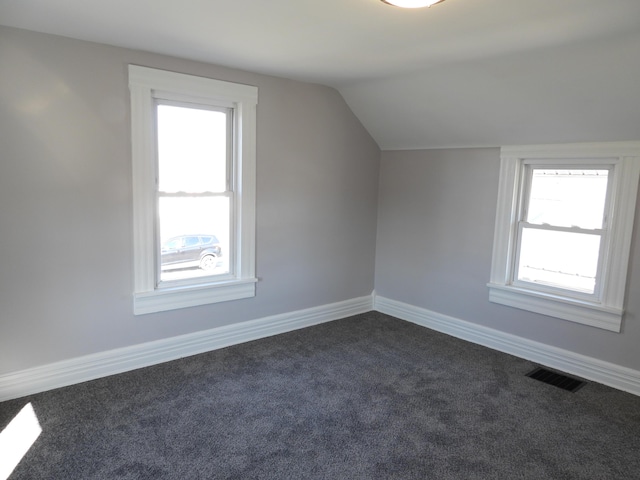 bonus room with visible vents, dark carpet, lofted ceiling, and baseboards