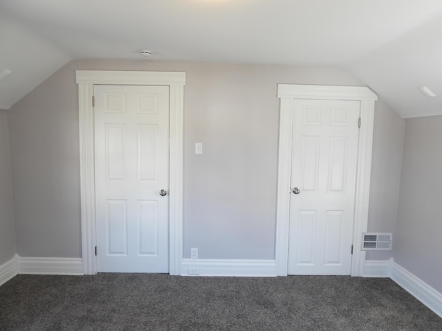 additional living space featuring visible vents, baseboards, lofted ceiling, and dark colored carpet