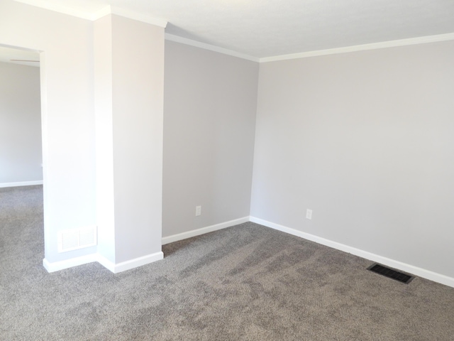 spare room featuring crown molding, baseboards, visible vents, and dark carpet