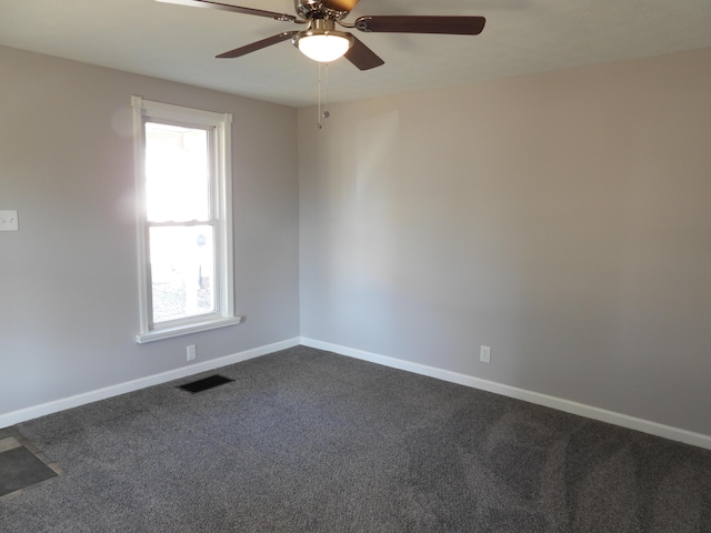 unfurnished room with plenty of natural light, visible vents, baseboards, and dark colored carpet