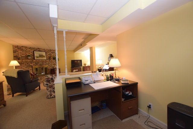 carpeted home office with a paneled ceiling and a brick fireplace