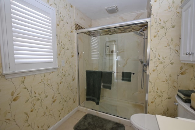 bathroom with tile patterned flooring, toilet, and a shower with shower door