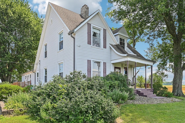 4711 N Elm Tree Rd, Conover, OH 45317 - view of front of home featuring a porch, a chimney, a shingled roof, and a front lawn