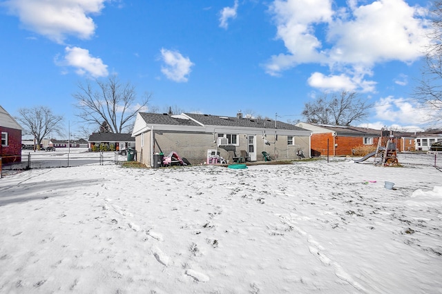 snow covered rear of property with a playground