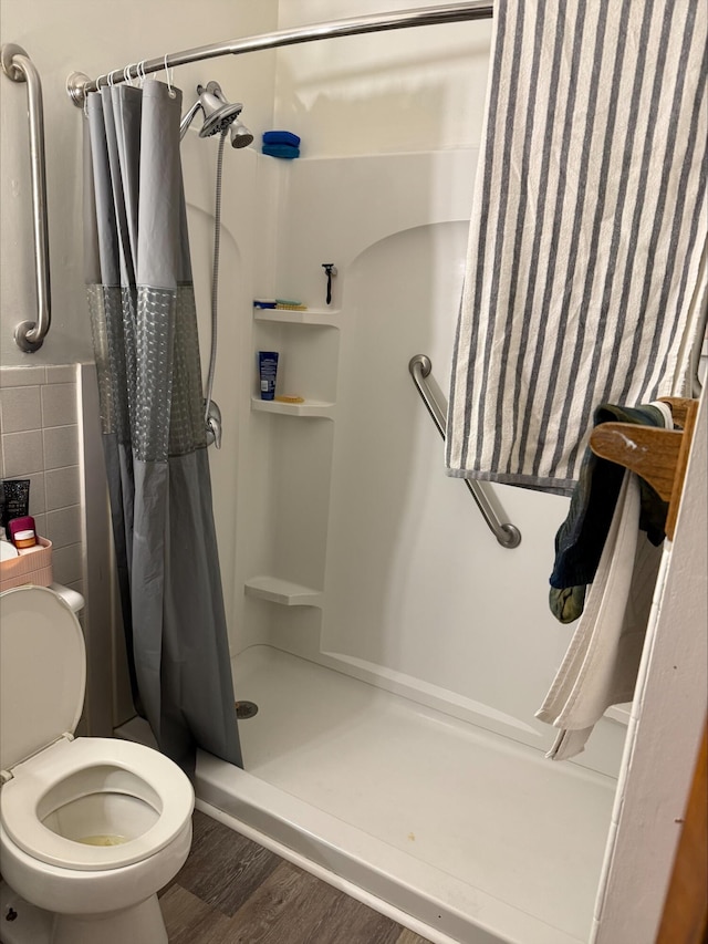 bathroom featuring wood-type flooring, toilet, and curtained shower