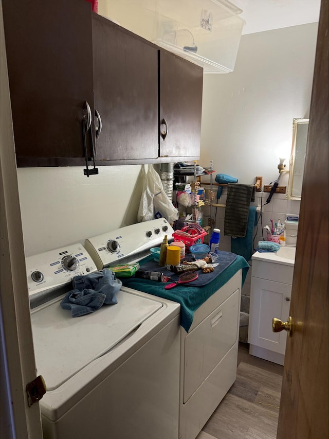 clothes washing area with cabinets, light hardwood / wood-style flooring, and independent washer and dryer