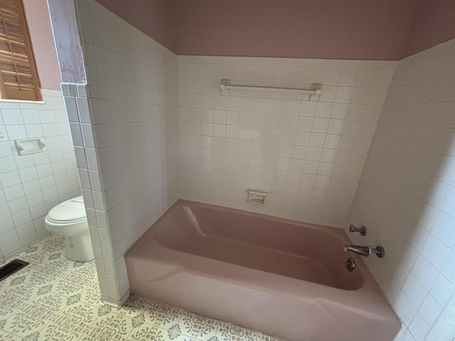 10081 Forest St, Lakeview, OH 43331 - bathroom featuring toilet, tile patterned flooring, tile walls, a wainscoted wall, and washtub / shower combination
