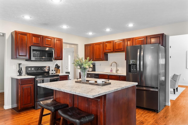 170 Fox Harbor Dr, Troy, OH 45373 - kitchen featuring stainless steel appliances, light wood-style flooring, a kitchen island, a breakfast bar area, and backsplash
