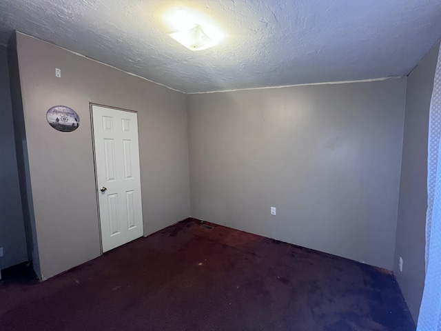 carpeted empty room featuring a textured ceiling