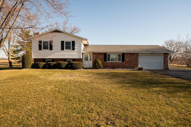 split level home with a front yard, an attached garage, a chimney, aphalt driveway, and brick siding