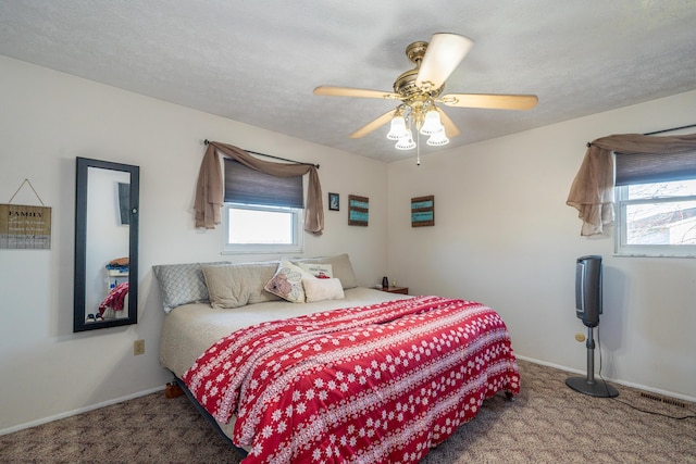 carpeted bedroom featuring ceiling fan, baseboards, and a textured ceiling