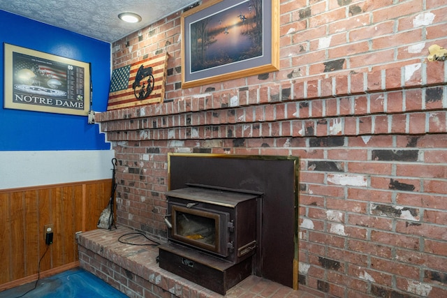 room details with a wood stove, wooden walls, wainscoting, and a textured ceiling