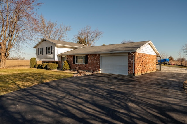 split level home with brick siding, an attached garage, driveway, and a front yard