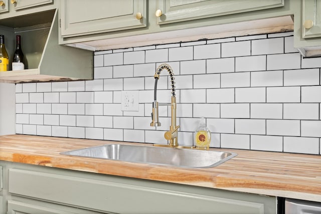 interior details with green cabinetry, sink, wood counters, and decorative backsplash