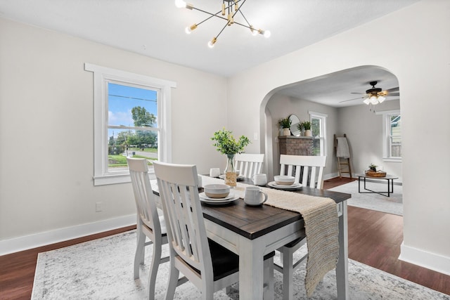 dining room with a healthy amount of sunlight, dark wood-type flooring, and a notable chandelier