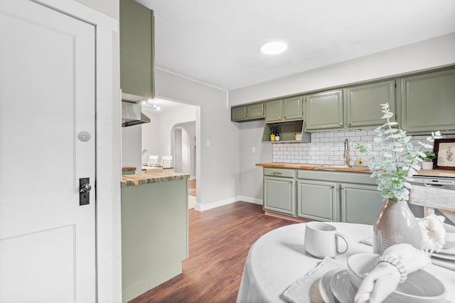 kitchen with dark hardwood / wood-style flooring, sink, backsplash, and green cabinetry