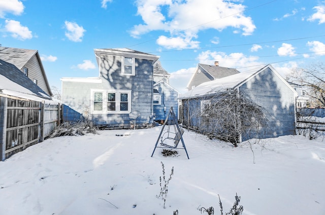 snow covered rear of property with fence