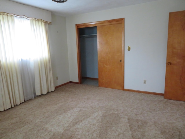 unfurnished bedroom with a closet, carpet floors, and baseboards