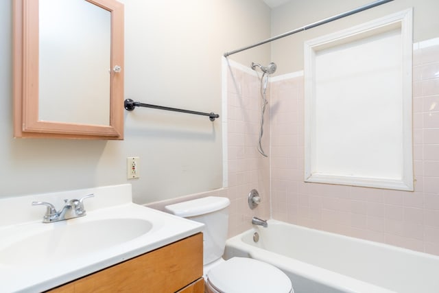 full bathroom featuring vanity, tiled shower / bath, and toilet