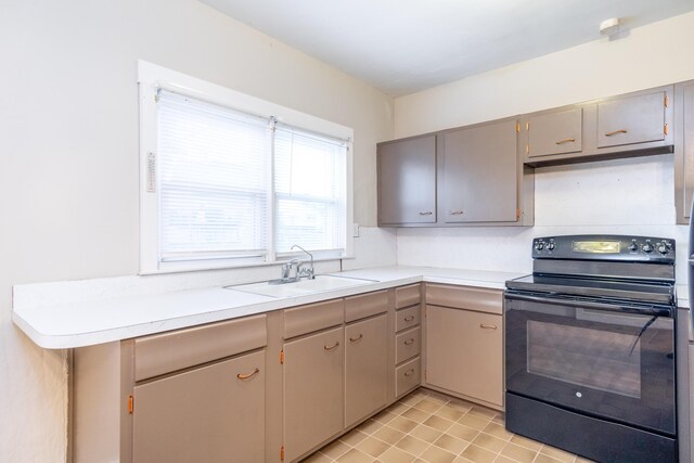 kitchen with light tile patterned flooring, sink, black electric range, and gray cabinetry