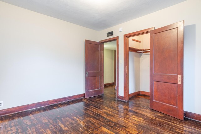 unfurnished bedroom with dark hardwood / wood-style flooring and a closet