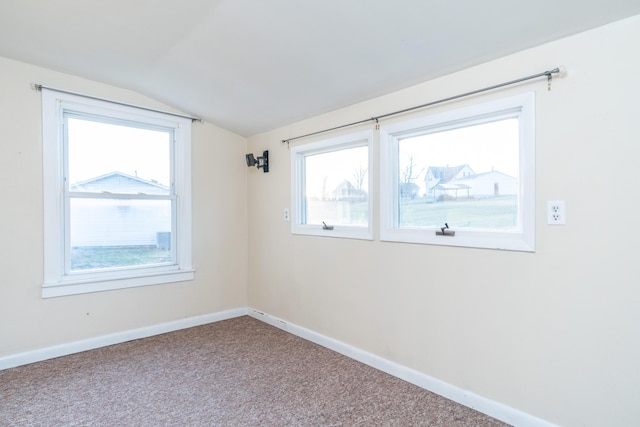 carpeted spare room featuring vaulted ceiling